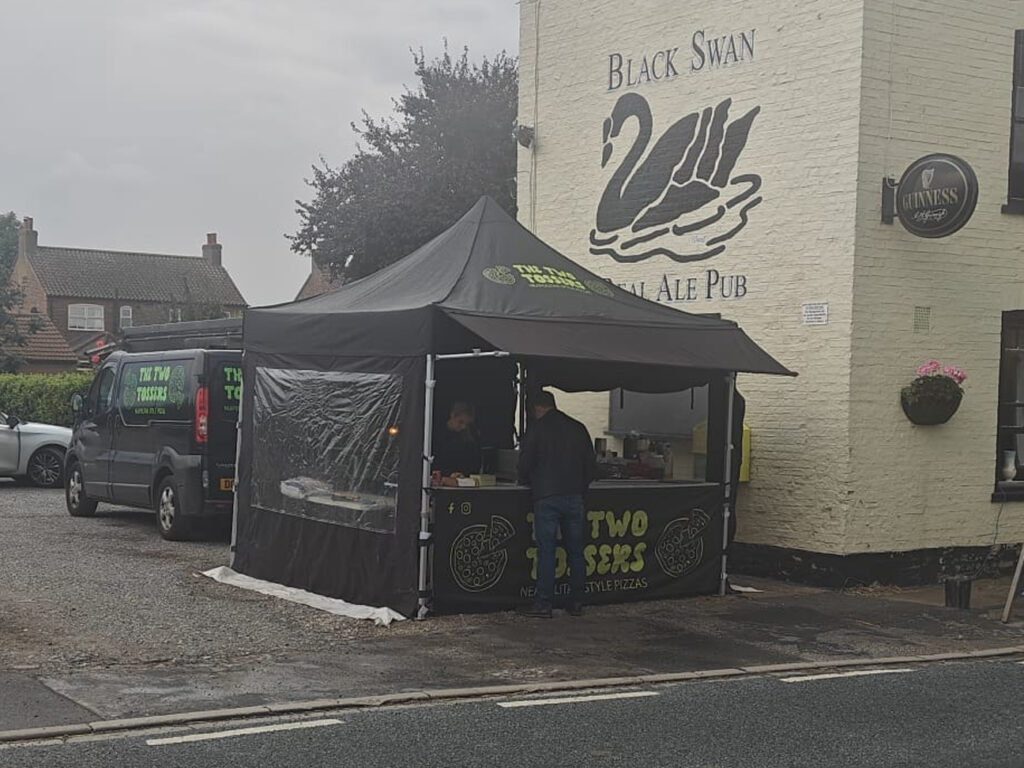 pop up pizza gazebo with a rain awning serving a customer outside a pub